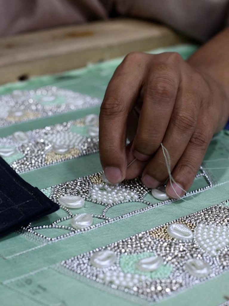 Master embroiderer's hands finishing a Ming-dynasty Hanfu collar